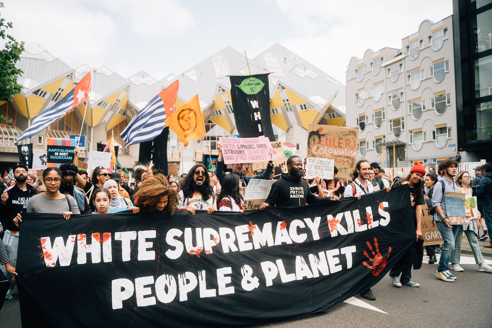 Deelnemers aan de Klimaatmars in Rotterdam dragen een banner met de tekst 'White supremacy kills people & planet'